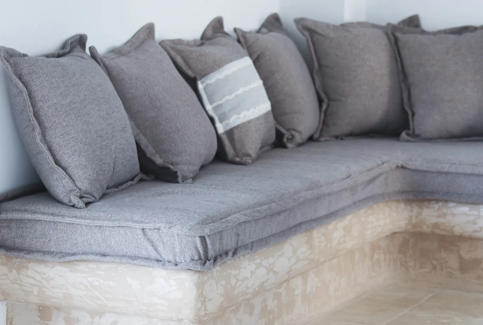 Built-in stone bench with grey cushions in Boreas