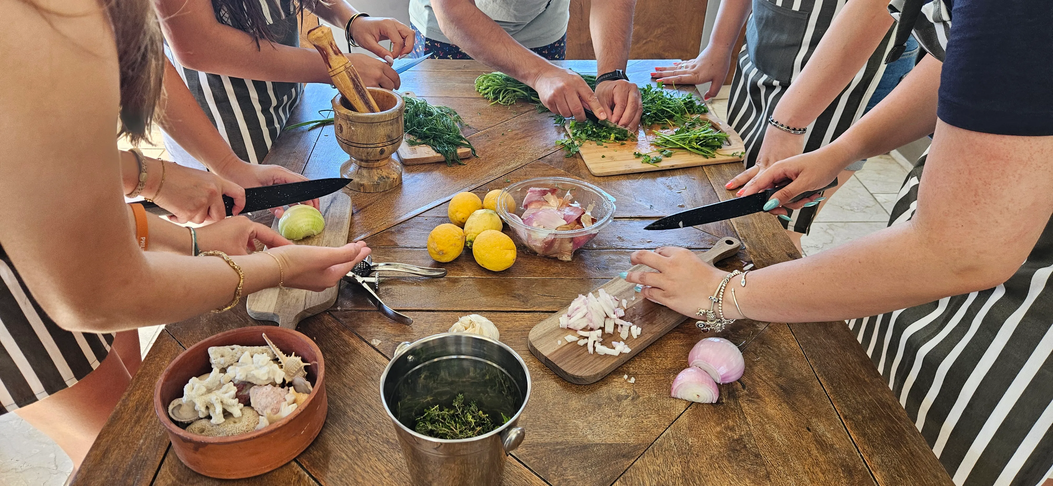 Guests preparing herbs and vegetables together at a wooden table