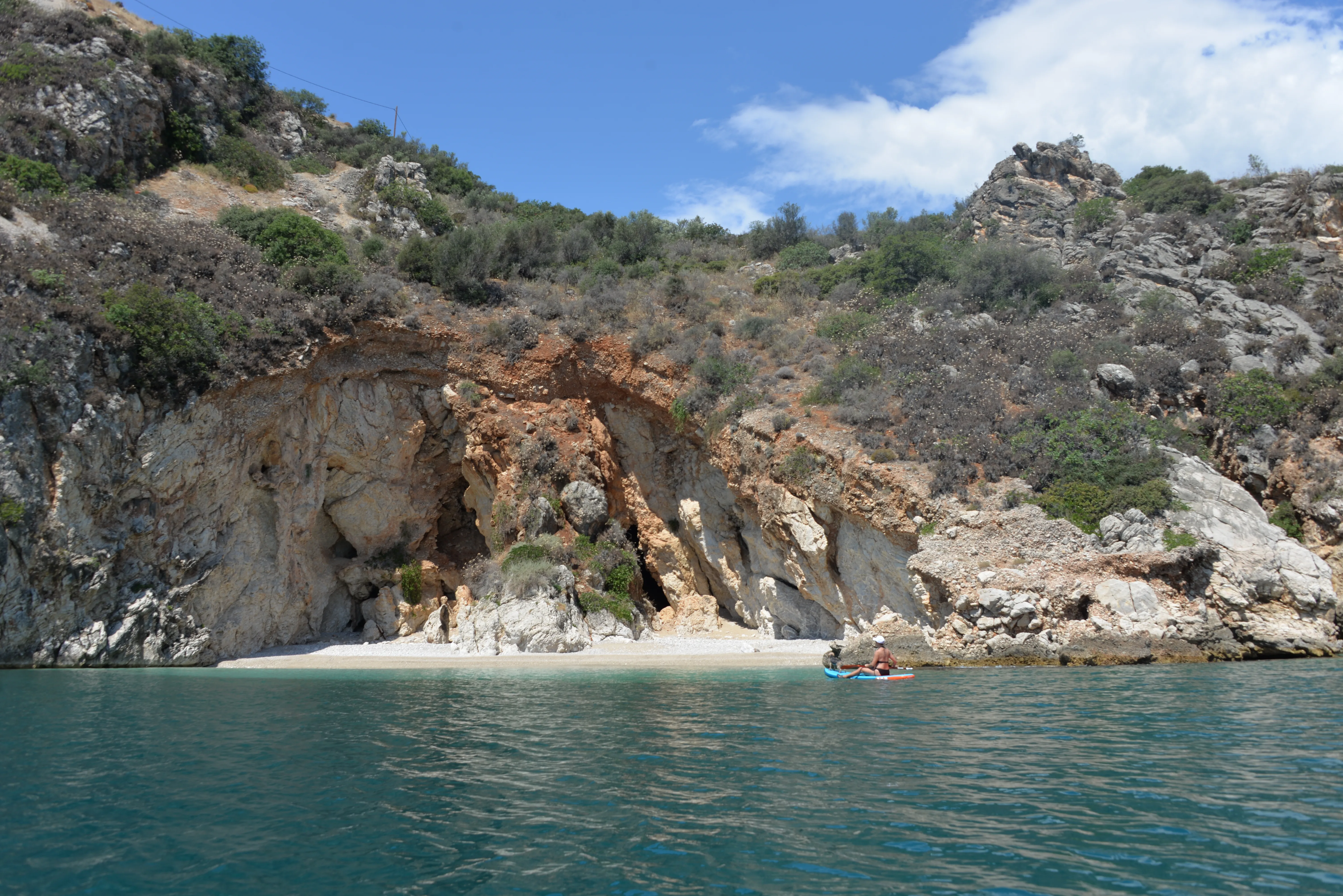 Kayak resting at a hidden pebble cove beneath ochre cliffs