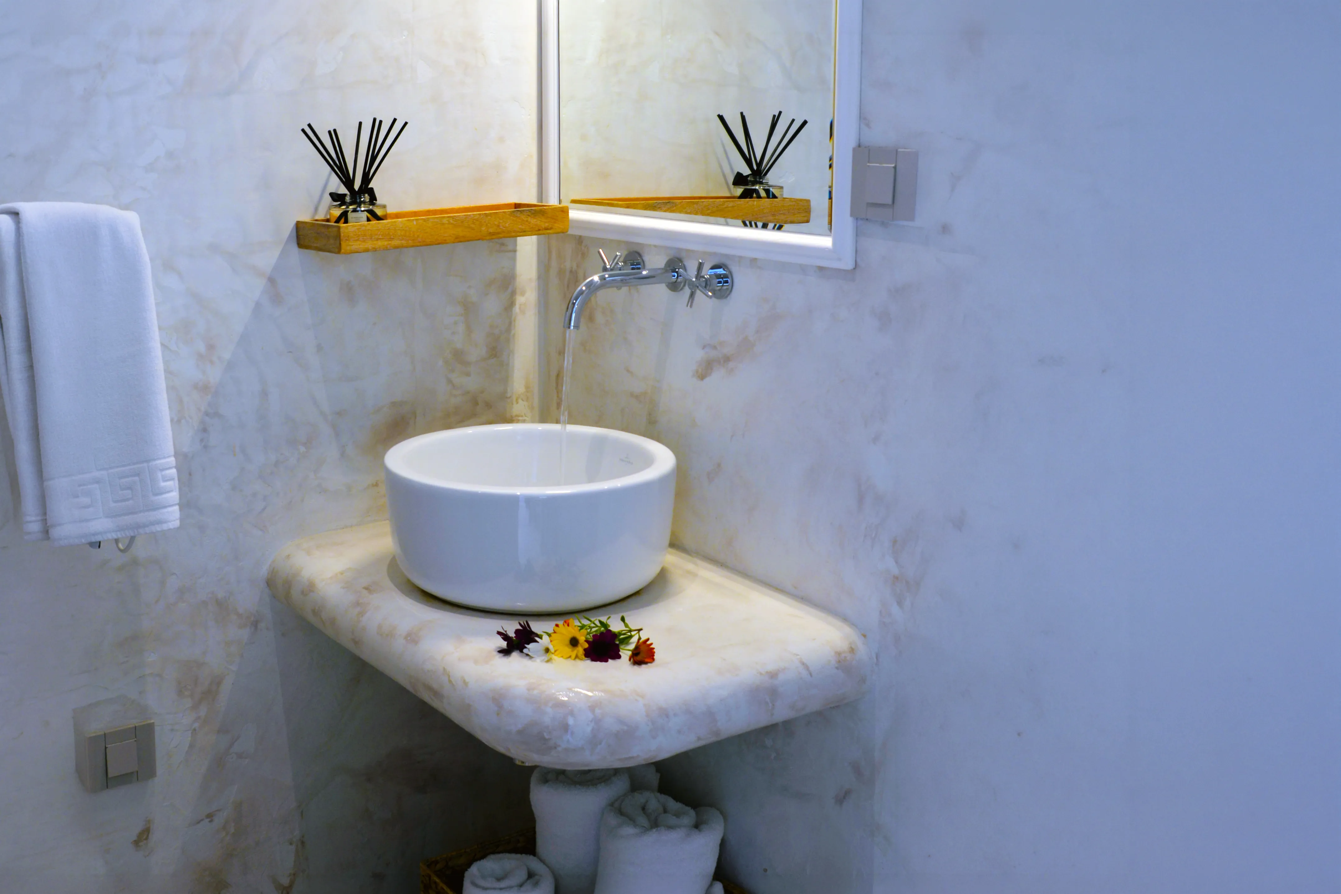 Bathroom basin on a marble shelf below a mirror