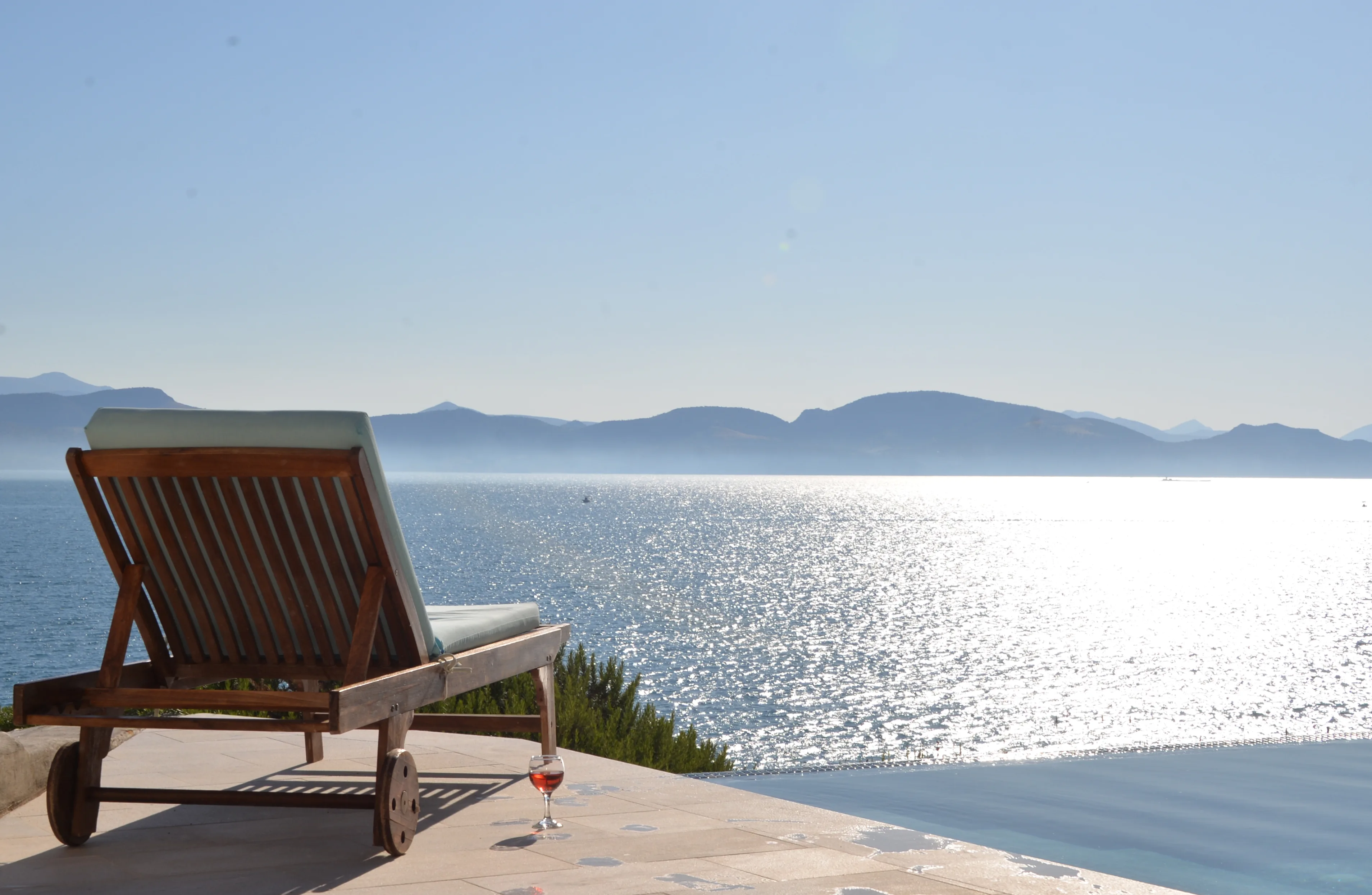 Lounger on the terrace facing the sunlit silver sea