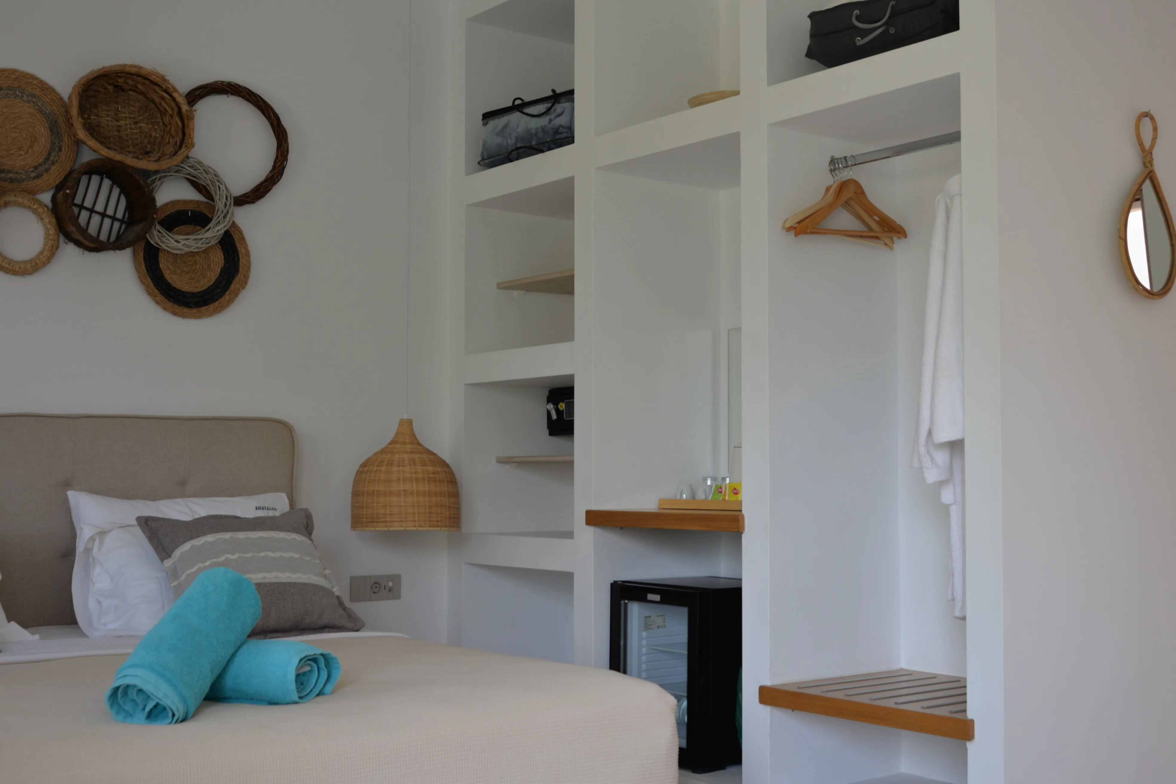 Lips bedroom with woven wall decor, open wardrobe and minibar